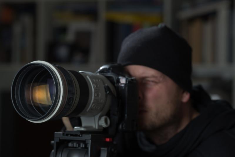 A Royal Security investigator conducting surveillance with a long-lens camera